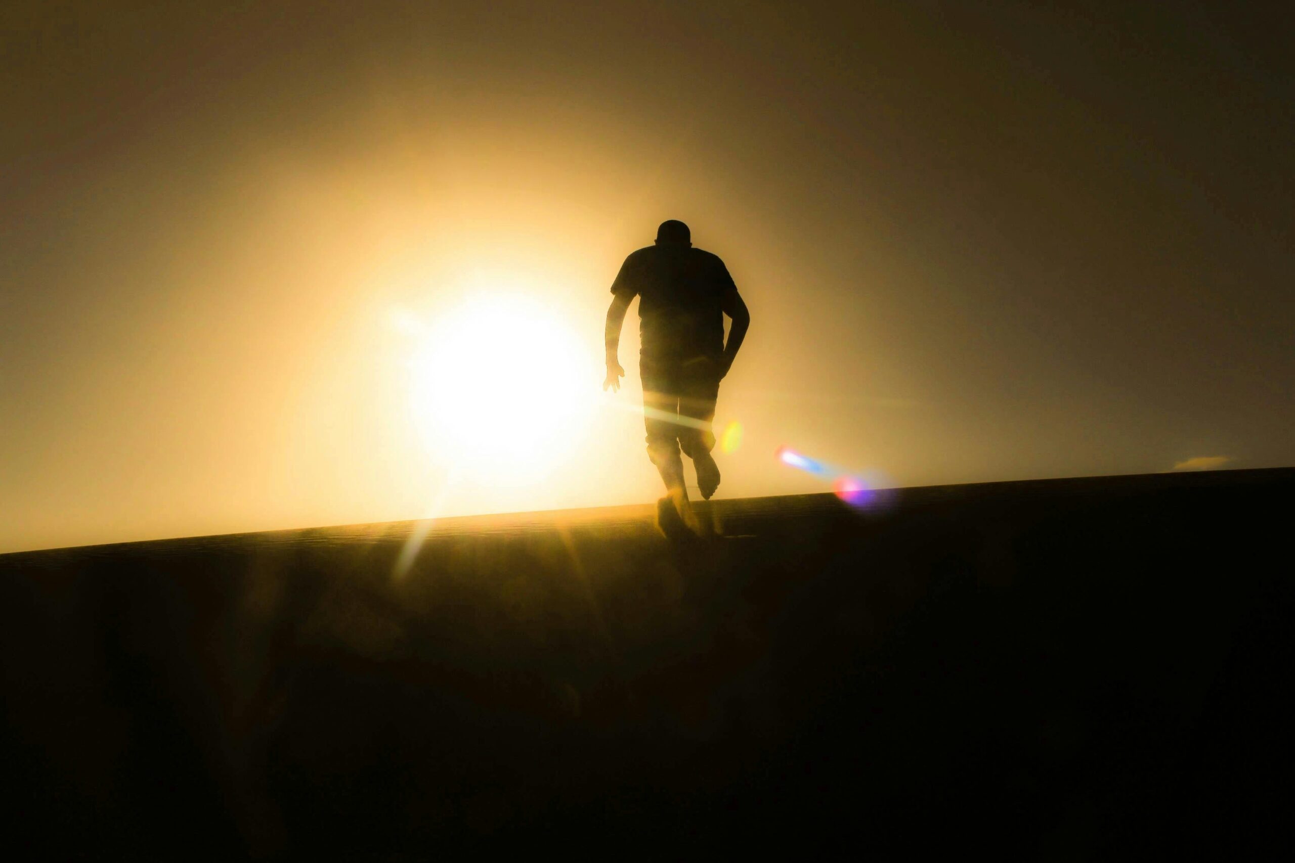Runner silhouetted against a glowing sun